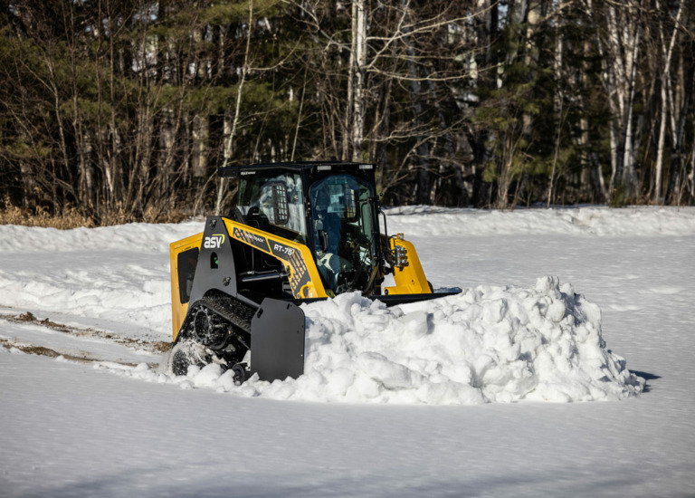 Skid steer clearing snow from a property